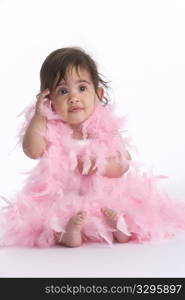 Baby Girl Sitting On The Floor Dressed In Pink Feathers Like A Diva