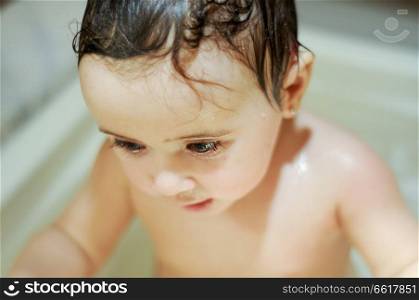 Baby girl six months old having her bath and crying