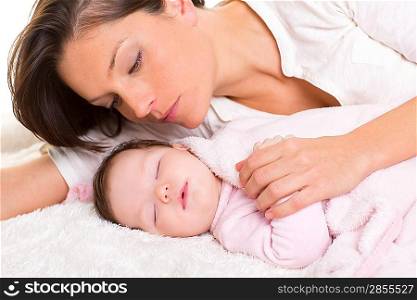 Baby girl sleeping with mother care near on white fur
