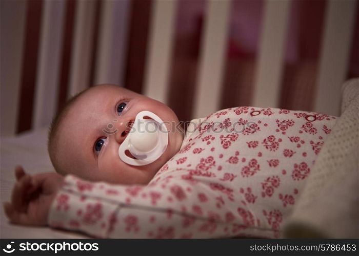 Baby Girl With Pacifier Lying In Cot