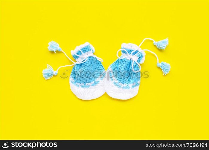 Baby gloves on yellow background. Top view