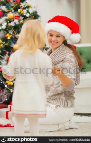 Baby helping mother decorate Christmas tree