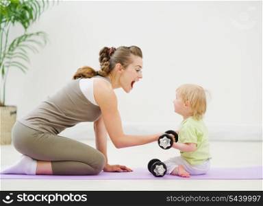 Baby helping mother lifting dumb-bells