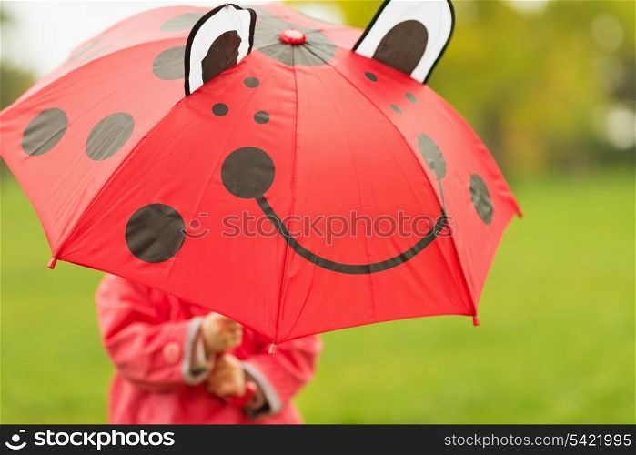 Baby hiding behind red umbrella