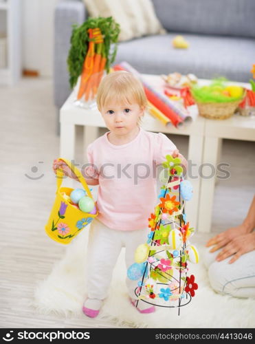 Baby holding basket of Easter eggs and decoration