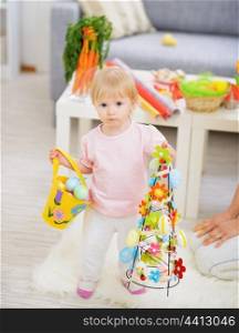 Baby holding basket of Easter eggs and decoration