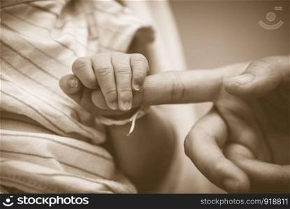 Baby holding mother fingers in concept of love and family. Closeup baby and mom palm hands. Newborn and infant tenderness. Health and trust of relationship people. Vintage tone film