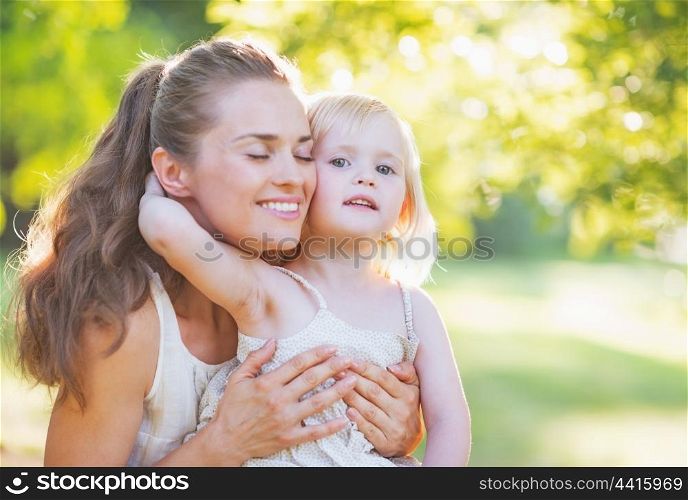 Baby hugging mother outdoors