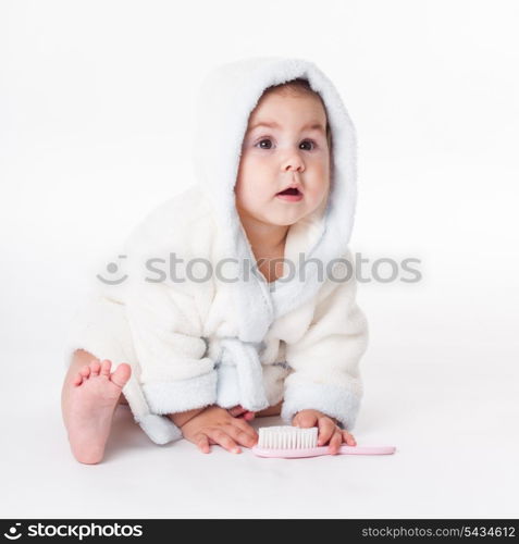 Baby in a bathrobe after bath with comb