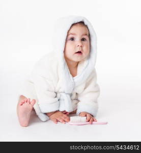 Baby in a bathrobe after bath with comb