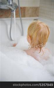 Baby in bath foam. Rear view