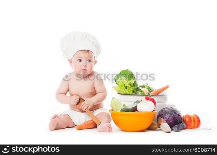 Baby in chef hat plays with vegatables isolated on white. Little chef cooks