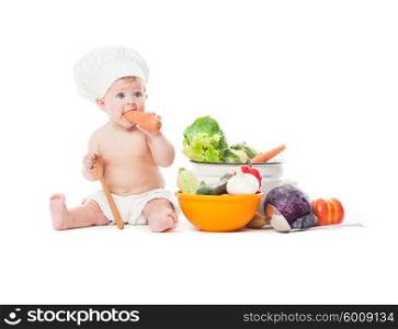 Baby in chef hat plays with vegatables isolated on white. Little chef cooks