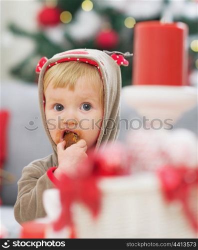 Baby in christmas costume eating cookie