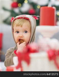 Baby in christmas costume eating cookie