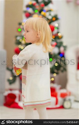 Baby in front of Christmas tree. Rear view