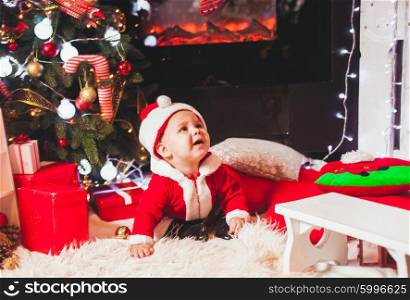 Baby in Santa costume play at Christmas decorations. Baby in Santa costume
