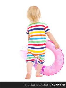 Baby in swimsuit playing with inflatable ring and beach ball. Rear view