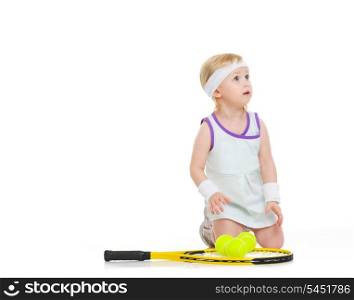 Baby in tennis clothes with racket and balls looking on copy space