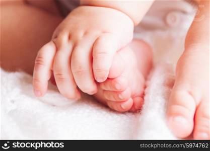 Baby is sitting on the textile. Hands and feet close up. Baby close up foot