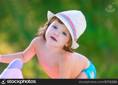 Baby kid girl with hat in summer on green field background
