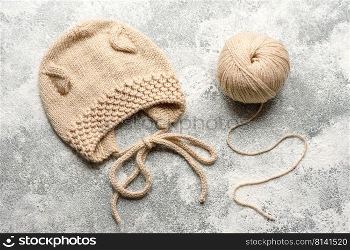 Baby knitted beige clothes on a white concrete background. Knitting in hand, hobby. Baby knitted beige clothes on a white concrete background