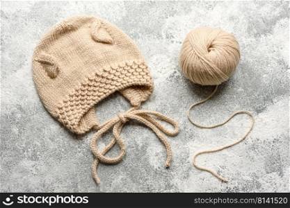Baby knitted beige clothes on a white concrete background. Knitting in hand, hobby. Baby knitted beige clothes on a white concrete background