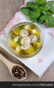 Baby mozzarella in olive oil with herbs in a glass jar