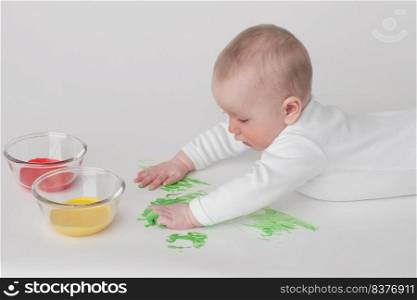 baby on a white background in a white pajamas with paints. baby on a white background