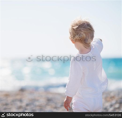 Baby on beach pointing into distance