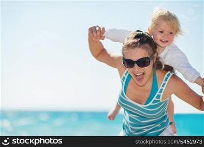 Baby piggybacking mother on beach
