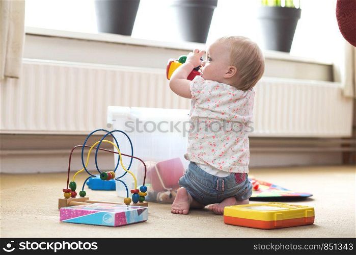 Baby playing alone with toys on a carpet on the floor at home messy. Baby playing alone with toys on a carpet on the floor at home