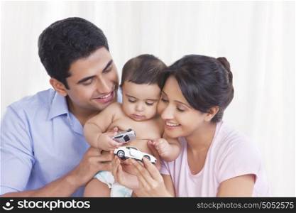 Baby playing with toy cars as parents look on