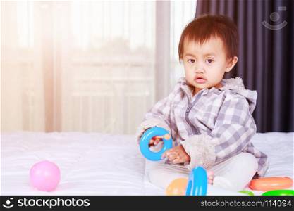 baby playing with toy on bed at home