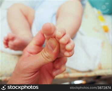 Baby receiving foot massage after diaper change with a thumb
