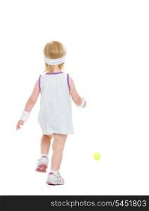 Baby running for tennis ball . rear view
