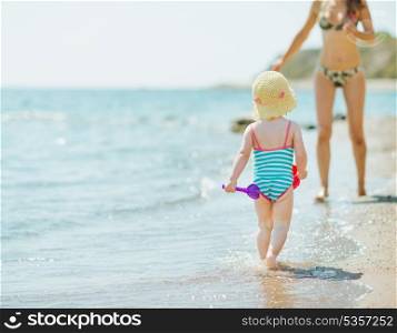 Baby running to mother along seashore