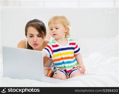 Baby showing something to mother in laptop