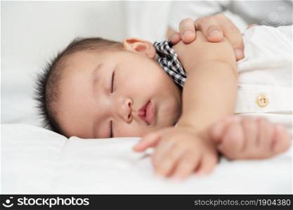 baby sleeping on a bed with hand patting