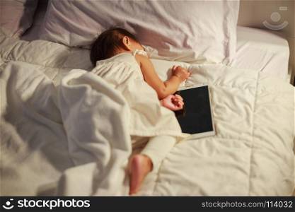baby sleeping on bed after playing digital tablet