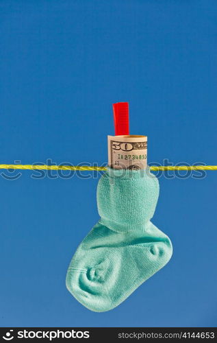 baby socks on clothesline with dollar bills. blue skies.