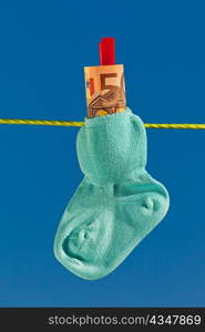 baby socks on clothesline with euro bills. blue skies.