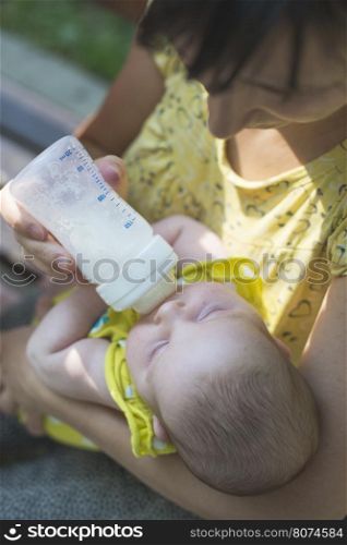 Baby sucks on a bottle. Baby in mother's hands