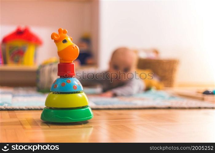 Baby toy on wooden floor, baby in the blurry background, copy space