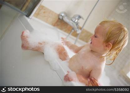 Baby trying to get out from bathtub