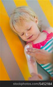 Baby waiting while mother applying sun block creme on arm