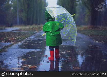 Baby walking in autumn rainy park