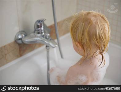 Baby washing in foamy bathtub