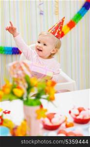 Baby with birthday gift pointing in corner