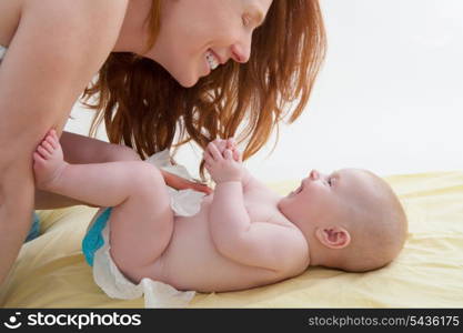 Baby with mother diapering and playing smiling having fun